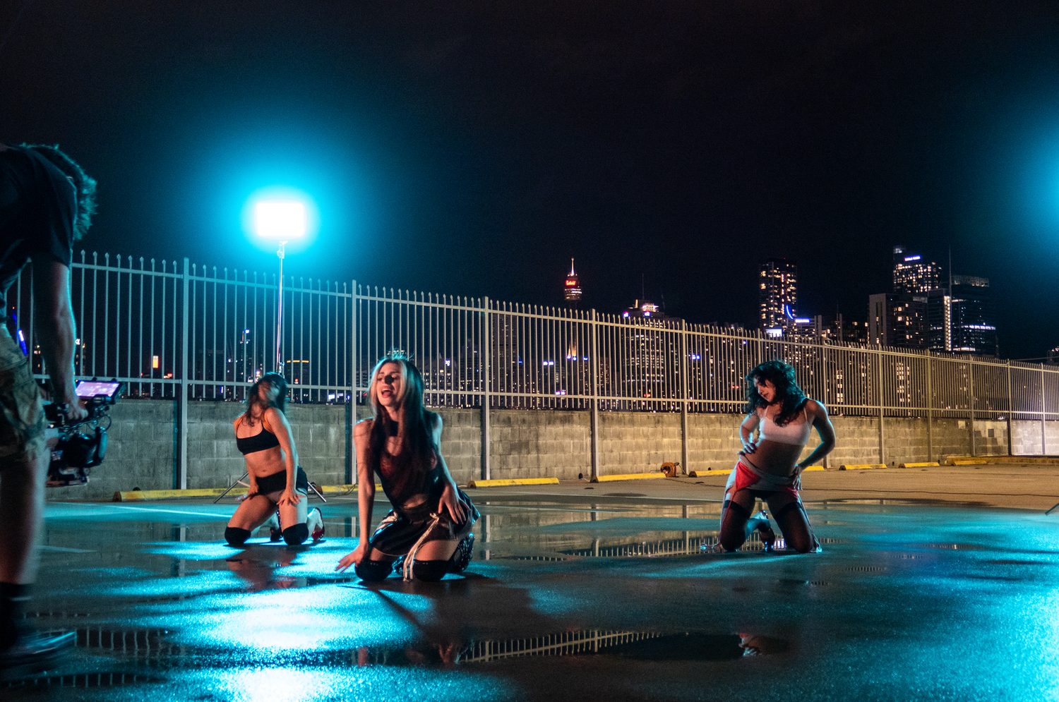 Dancers kneeling on a rooftop at night with the city behind
